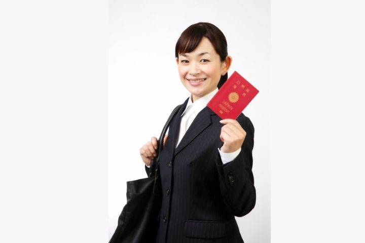 パスポートを持ちスーツを着た女性の画像