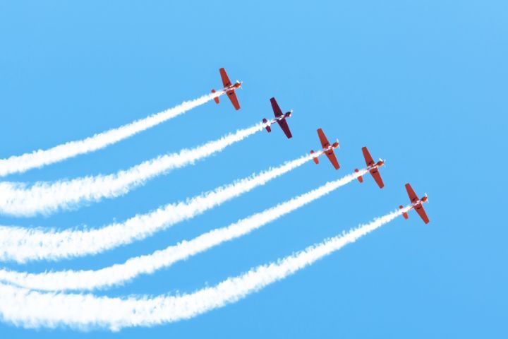 飛行機雲を出しながら空を飛ぶ5つの飛行機のイメージ