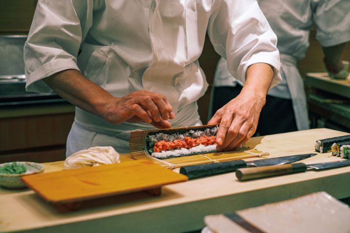 寿司職人が巻き寿司を作っているイメージ