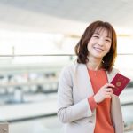 パスポートを持って微笑むビジネスウーマンの女性のイメージ