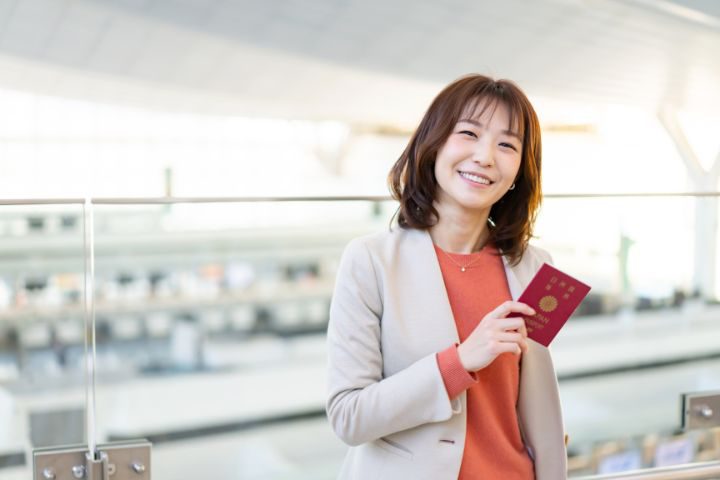 パスポートを持って微笑むビジネスウーマンの女性のイメージ