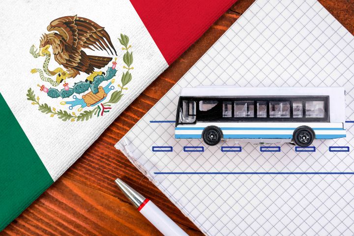バスのミニチュア模型と筆記用具、メキシコの旗のイメージ