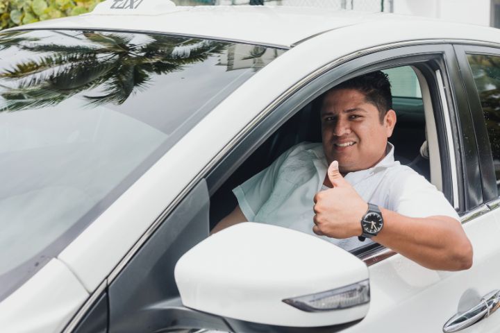 メキシコ人の男性ドライバーが車の窓からOKサインを出しているイメージ