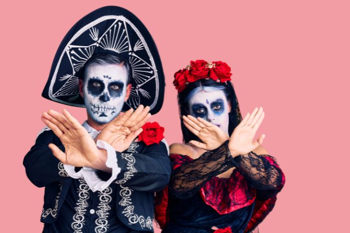 Dia de muertosの衣装を着てバツサインのポーズをとっているメキシコ人のイメージ