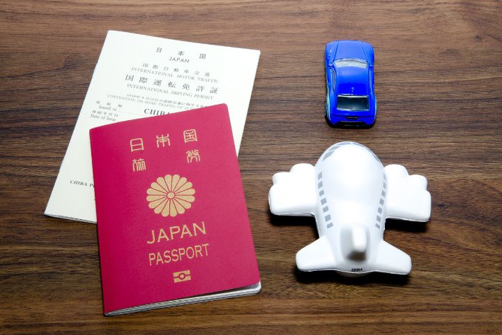 日本の国際運転免許証とパスポート、車と飛行機のミニチュアのイメージ 