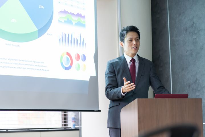 プレゼンテーションでアピールしている日本のビジネスマンの画像