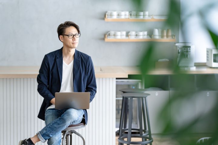 カフェでパソコンで仕事している日本人男性の画像