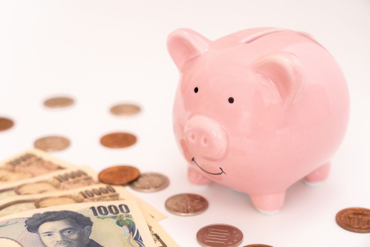 ピンクの豚の貯金箱と日本札と小銭の画像