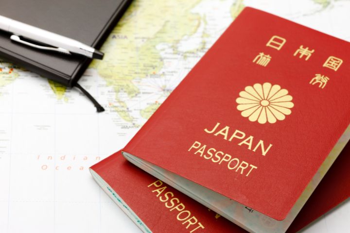日本の赤いパスポートが世界地図の上に置いてある画像