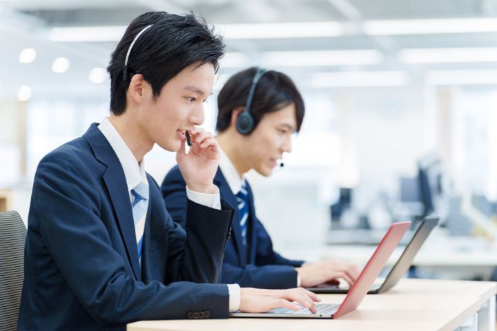 コールセンターで働く若い日本人男性の画像