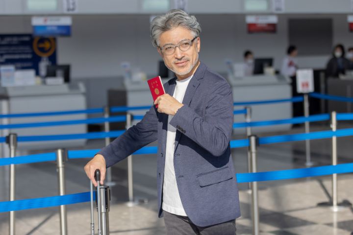 パスポートとキャリーケースを持って歩く男性のイメージ